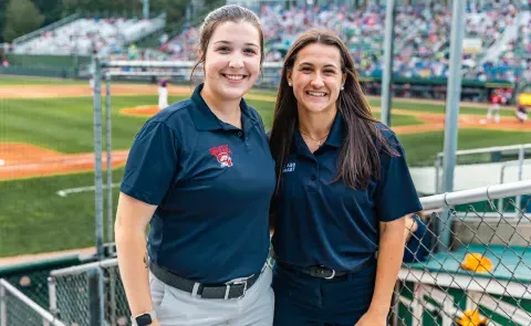 Two UNE business students pose in front of the baseball diamond at Portland's Hadlock Field